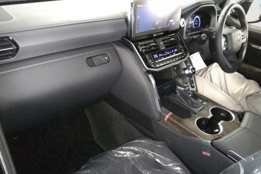 Interior of a Toyota Land Cruiser with auction details displayed on a smartphone screen.