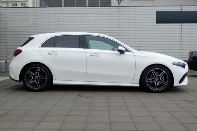 White car parked on a tiled pavement with a building in the background