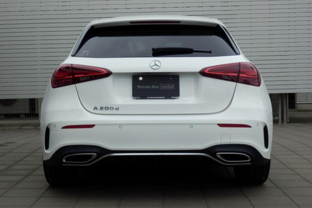 White Mercedes-Benz car parked in front of a gray building