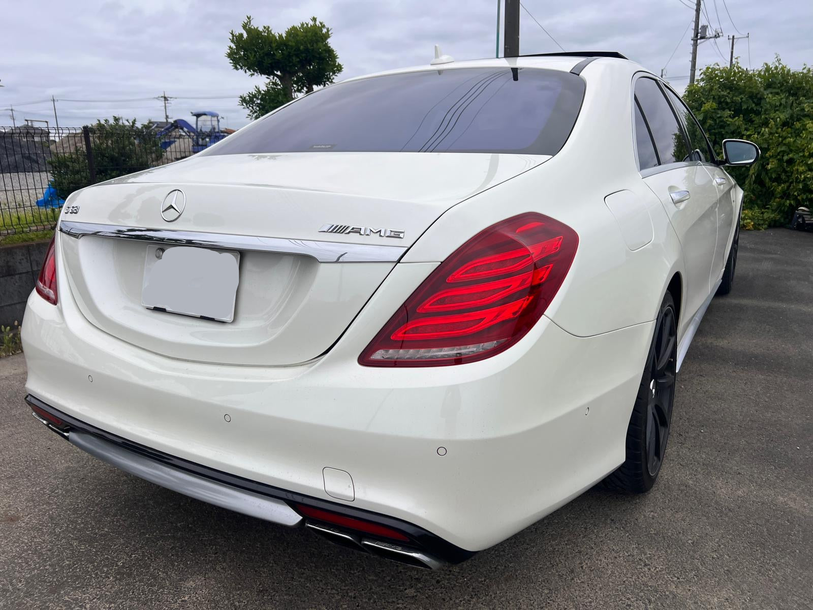 White Mercedes-Benz car parked on a road with a cloudy sky in the background