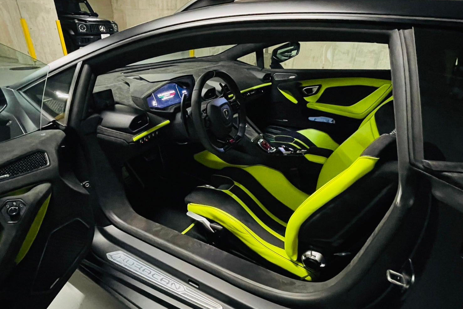 Car interior with lime green seats and dashboard, featuring a Lamborghini logo.
