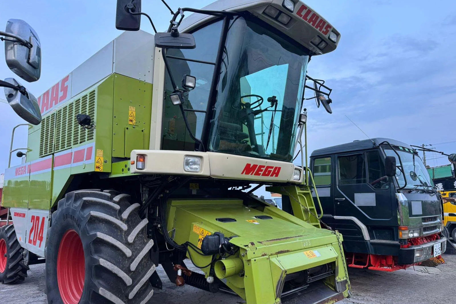 Green agricultural combine harvester with 'Mega' branding in an outdoor setting.
