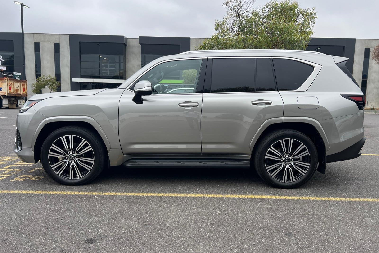 Silver SUV parked on a street with a building and trees in the background