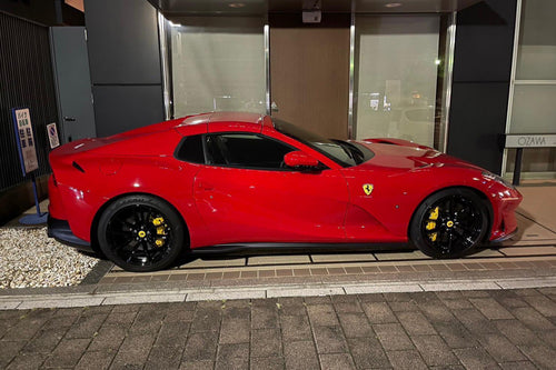 Red sports car parked on a street with a building in the background