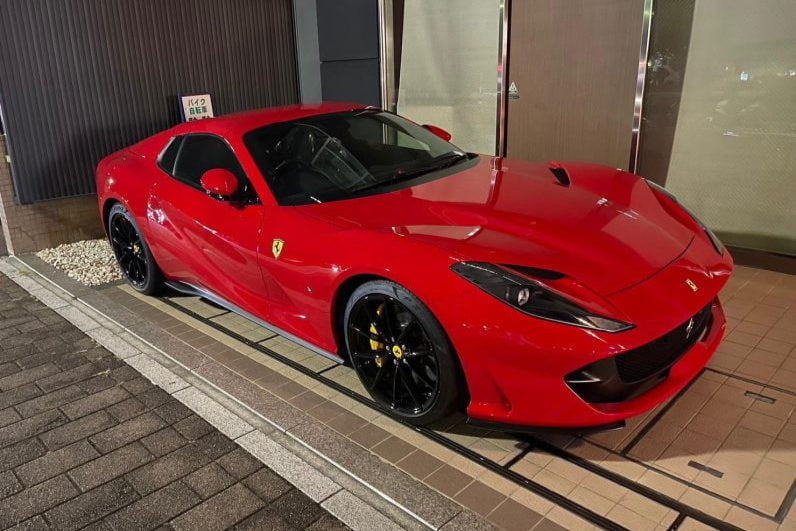Red Ferrari sports car parked on a tiled pavement
