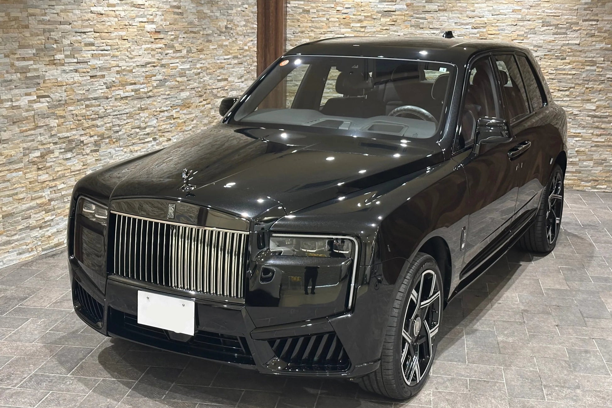 Black luxury SUV parked indoors with a stone wall background