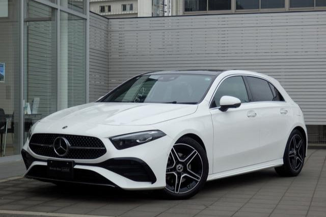 White Mercedes-Benz car parked on a city street with buildings in the background