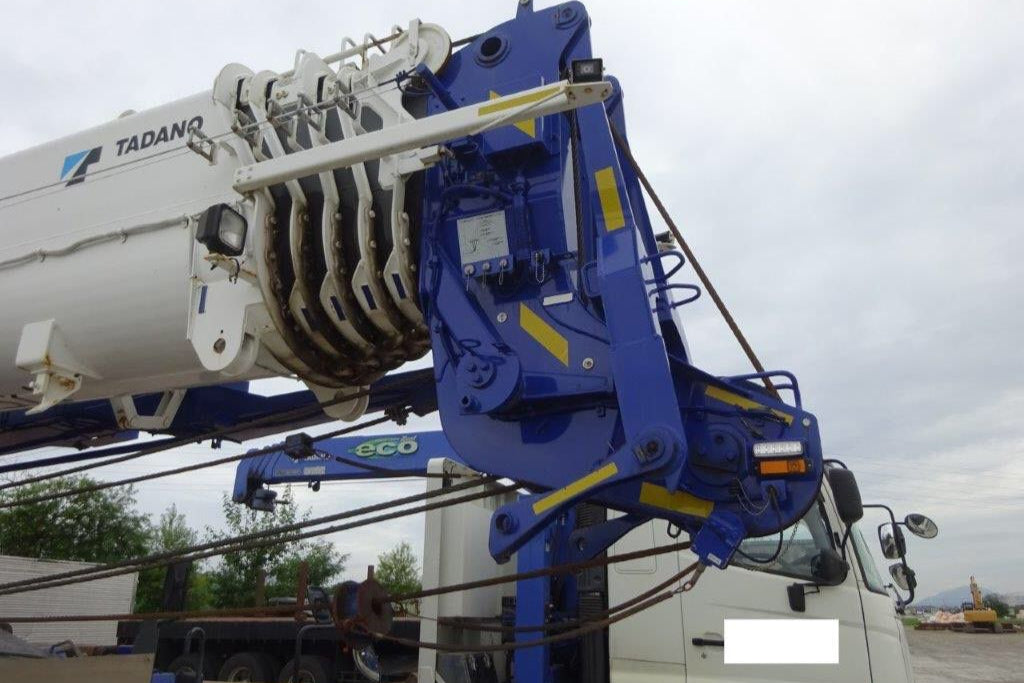 Blue crane arm attached to a truck with a cloudy sky background