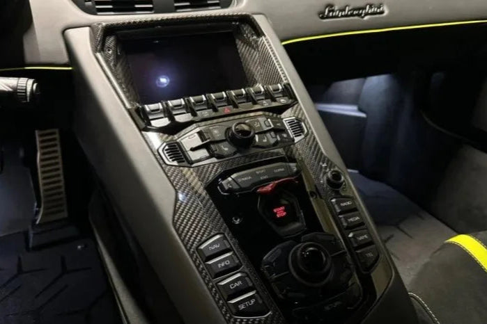 Close-up of a car's center console with carbon fiber finish and Infiniti logo.