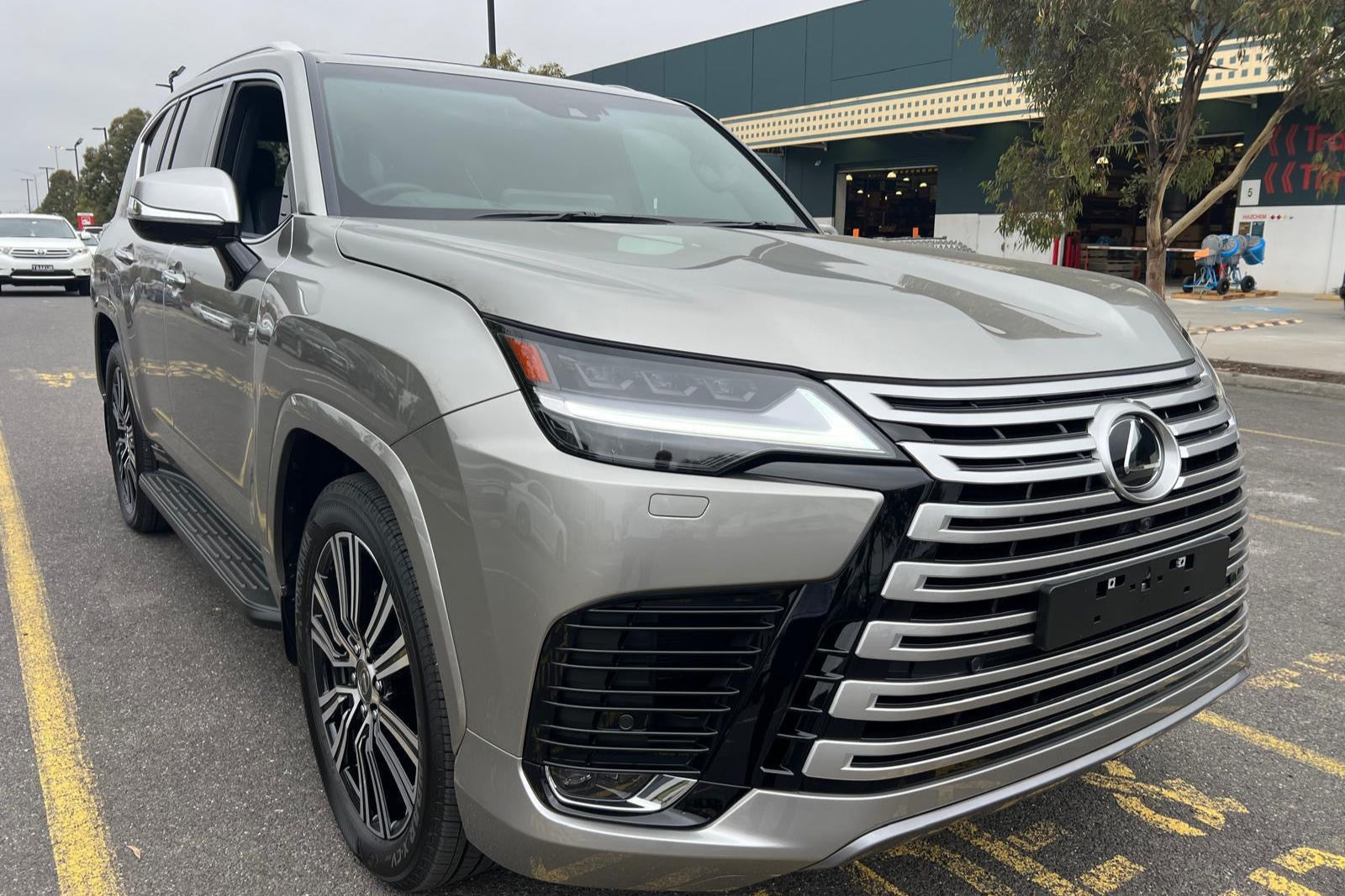 Silver SUV parked on a street with a building and trees in the background